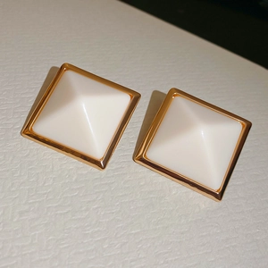 Gros plan de boucles d'oreilles géométriques en résine avec bordure dorée et relief