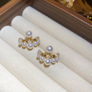 Macro shot of elegant gold earrings with white pearls and micro-inlaid sparkling diamonds