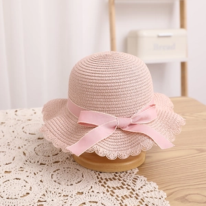 Détail d'un chapeau de paille rose pour fille avec nœud en soie et bordure dentelle