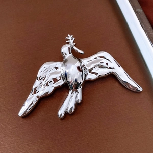 Macro della spilla a forma di colomba d'argento con trama astratta e finitura lucida