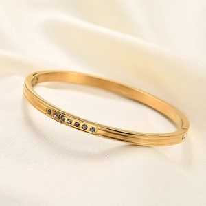 Detail showing the 18K gold-plated bangle with grey zircon inlay on white silk