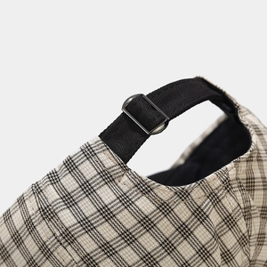 Detail of the adjustable metal buckle and black strap on the vintage plaid newsboy cap