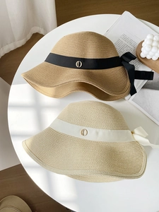 Detail of wide brim straw hats with elegant bow ribbons and metallic buckle accents
