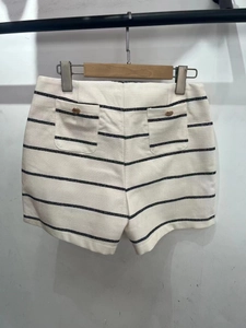 Detail view of cream striped knit shorts with metal button accents and textured fabric