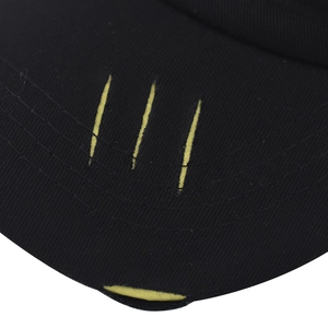 Détail de la visière de casquette noire délavée avec déchirures jaunes et surpiqûres