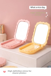 Close-up of portable cookie-shaped makeup mirror and comb set in pink and yellow colors