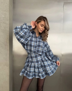 Detailed view of blue plaid dress showing tiered ruffle hem and bubble long sleeves