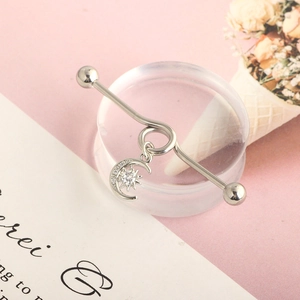 Detailed view of silver industrial barbell earring with sparkling moon and star pendant