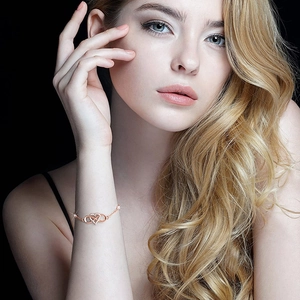 Elegant rose gold infinity heart bracelet with shimmering zircons on a model's wrist