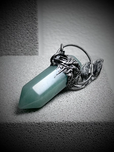 Macro detail of hexagonal green stone pendant with vine silver base and leaf charms