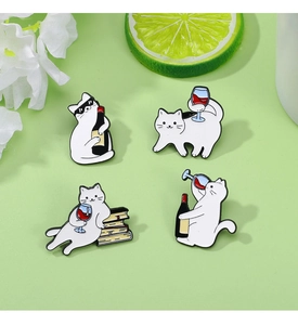 Detail of four white cartoon cat enamel pins with red wine motifs on a green background