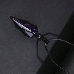 Detailed macro shot of a purple crystal pendulum pendant with black woven mesh cord