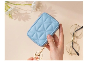 Macro view of light blue quilted makeup pouch with gold zipper and keyring detail