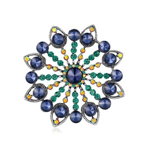 Detail shot of a vintage silver flower brooch with deep blue and green gemstone petals