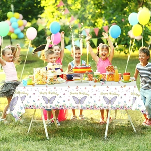 Children celebrating at an outdoor party table with purple butterfly birthday tablecloth