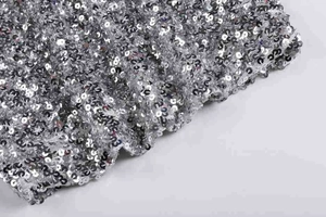 Détail macro du tissu à paillettes argentées avec textures rondes métalliques denses