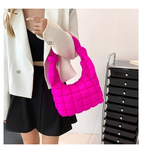 Detail of hot pink quilted puffer bag featuring a knotted handle and vibrant nylon texture