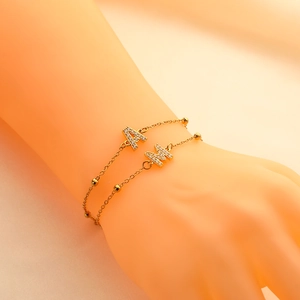 Detail of two gold-plated letter A and M charm bracelets with crystal pavé and beads