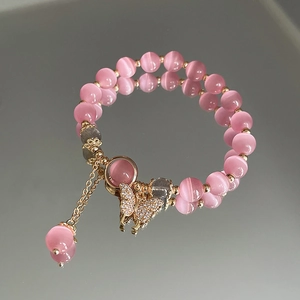 Detailaufnahme rosa Katzenaugen-Perlenarmband mit Goldakzenten und Schmetterling-Anhänger