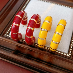 Detail view of vintage enamel C-shaped hoop earrings in red and yellow with gold accents