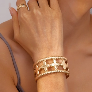 Detail of gold floral cutout cuff bracelet and ring set with beaded edges on model