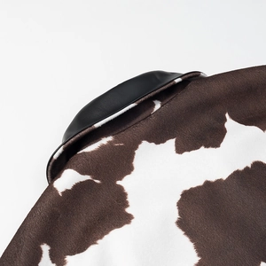Macro detail of cow print faux fur fabric and black leather stitching on a street jacket