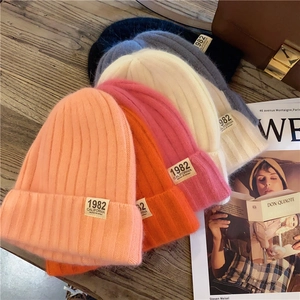 Flat lay of colorful ribbed knit beanies with 1982 California patches on wooden surface