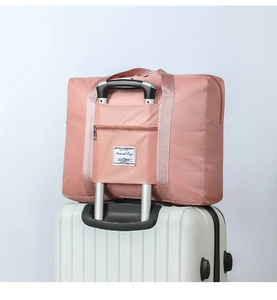 Detail of pink travel bag with luggage sleeve attachment on suitcase handle