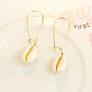 Detail of bohemian gold U-shaped earrings with natural white cowrie shell pendants