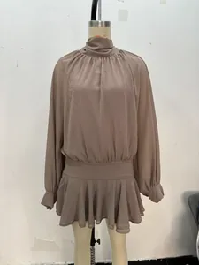 Detalle del vestido corto marrón morandi de manga larga con dobladillo plisado y cuello alto
