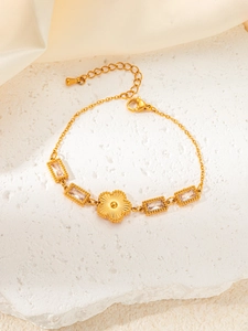 Detail of gold chain bracelet with emerald-cut zircons and central 3D floral charm