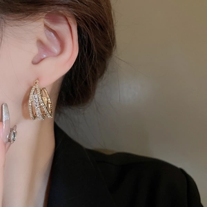 Close-up of three-layer gold geometric earrings with pavé white zircon on a model