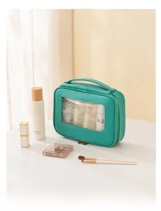 Dettaglio della borsa da toilette in pelle verde con finestra trasparente e cerniera oro