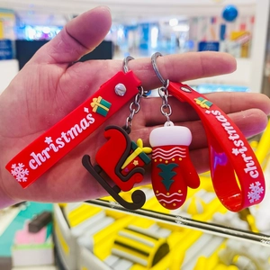 Christmas keychain with red silicone strap, santa glove and sleigh charms in hand
