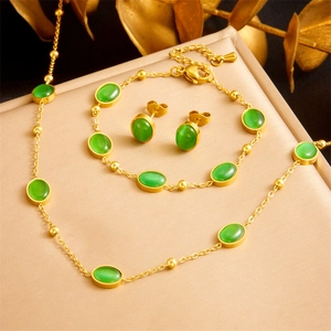 Elegant gold stainless steel jewelry set with oval green emerald stones on satin background