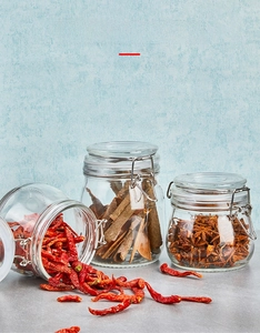 Detail of airtight glass jars with steel buckles storing various dried spices on a table