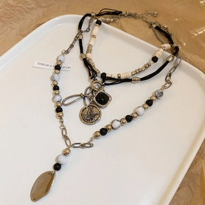Detail view of layered bohemian necklace with butterfly relief and vintage silver charms