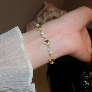 Detailed shot of green zircon and pearl bracelet with vintage gold chain on wrist