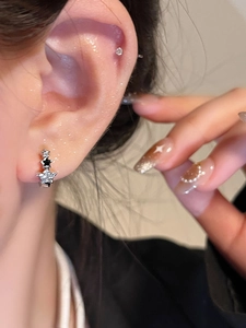 Primer plano de pendientes de estrella plateados con circonitas brillantes en oreja modelo