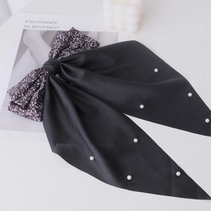 Detail of a floral print fabric bow hair clip with elegant long ribbons and white pearls