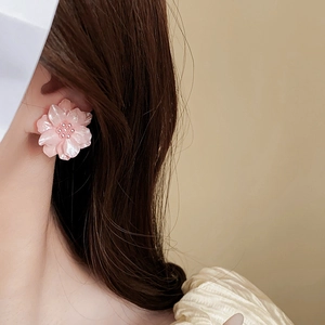 Gros plan détaillé d'une boucle d'oreille fleur en acrylique rose avec perle sur un mannequin