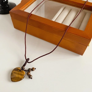 Macro detail of heart-shaped tiger eye stone pendant on woven rope necklace