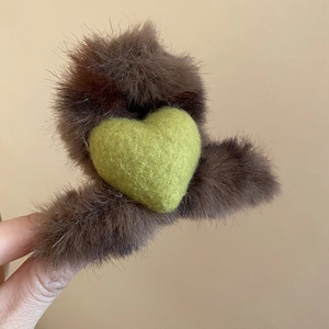 Détail de la pince à cheveux en peluche marron avec un cœur vert pour les coiffures d'hiver