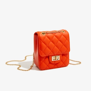 Detail of orange quilted PU leather crossbody bag with gold chain and twist-lock buckle