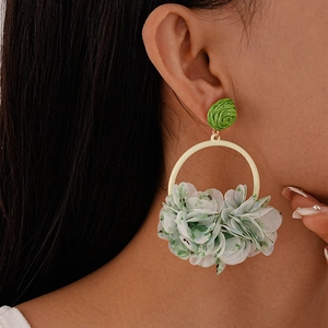 Detail view of model wearing green fabric flower earrings with geometric woven beads