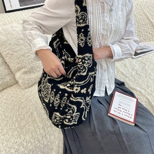 Detail of plush black and white totem pattern large shoulder bag on a cozy sofa