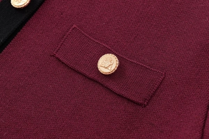Detail of burgundy knit cardigan featuring gold crest buttons and flap pocket texture