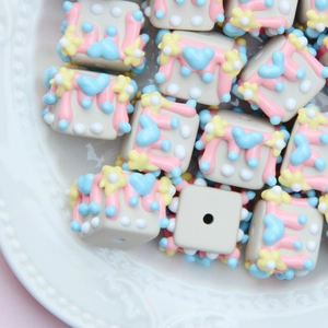 Close-up of colorful heart pattern square resin beads on a white tray for DIY crafts