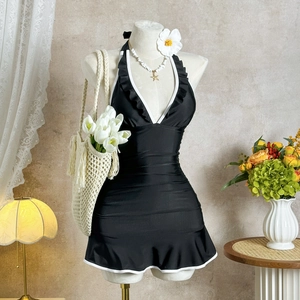 Detail of black halter one-piece swimsuit with white ruffle trim on a mannequin