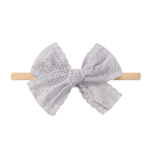 Détail du bandeau bébé avec nœud en dentelle grise et tissu en nylon beige extensible